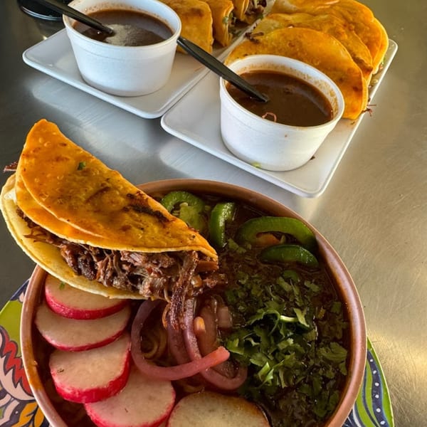 Birria tacos with consommé, radishes, pickled onions, cilantro, and jalapeños from Birria - Bite los Arcos.