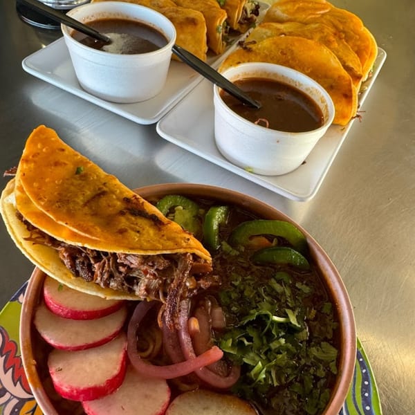Birria tacos with consommé, radishes, red onions, jalapeños, and cilantro from Birria - Bite los Arcos.